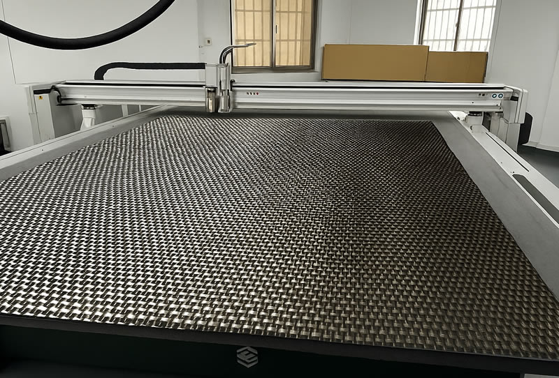 Dyneema 纖維布平鋪於數位切割機床台上,準備進行多層裁切